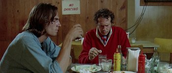 Movie still from “Two-Lane Blacktop” (1971), directed by Monte Hellman – Two men sitting at a table with a plate of food; Medium shot, Low angle