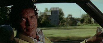 Movie still from “Two-Lane Blacktop” (1971), directed by Monte Hellman – A man sitting in the passenger seat of a car; Close Up shot, Low angle