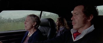 Movie still from “Two-Lane Blacktop” (1971), directed by Monte Hellman – Two women and a man sitting in the back of a car; Medium shot, Low angle