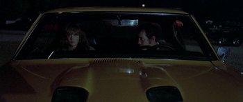 Movie still from “Two-Lane Blacktop” (1971), directed by Monte Hellman – A man and a woman sitting in the back seat of a yellow car; Medium shot, High angle