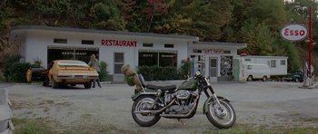 Movie still from “Two-Lane Blacktop” (1971), directed by Monte Hellman – A motorcycle parked in front of a restaurant; Wide shot, High angle
