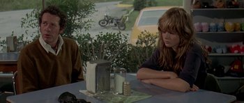 Movie still from “Two-Lane Blacktop” (1971), directed by Monte Hellman – A woman sitting at a table with two other people; Medium shot, Over the shoulder angle