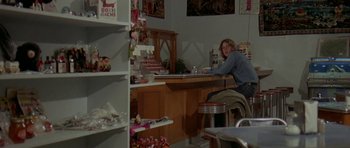 Movie still from “Two-Lane Blacktop” (1971), directed by Monte Hellman – A woman sitting at a table in a room; Medium shot, High angle