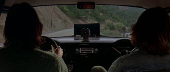 Movie still from “Two-Lane Blacktop” (1971), directed by Monte Hellman – A person is driving a car on the road; Wide shot, High angle