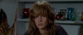 Movie still from “Two-Lane Blacktop” (1971), directed by Monte Hellman – A woman with long brown hair sitting in front of a shelf; Close Up shot, Low angle