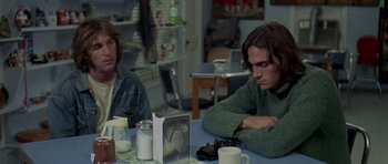 Movie still from “Two-Lane Blacktop” (1971), directed by Monte Hellman – Two people sitting at a table in a room; Medium shot, Over the shoulder angle