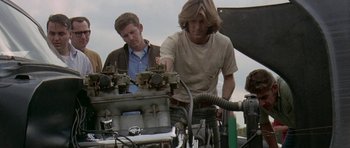 Movie still from “Two-Lane Blacktop” (1971), directed by Monte Hellman – Two men are working on a car engine; Medium shot, Low angle