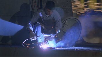 Movie still from “U-571” (2000), directed by Jonathan Mostow – A man welding a piece of metal in a shop; Medium shot, Low angle