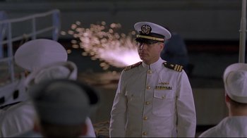 Movie still from “U-571” (2000), directed by Jonathan Mostow – A man in a white uniform is standing in front of fireworks; Medium shot, Low angle