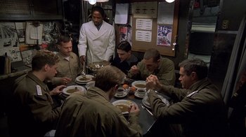 Movie still from “U-571” (2000), directed by Jonathan Mostow – A group of men sitting around a table eating; Medium shot, High angle