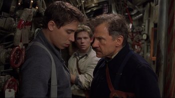 Movie still from “U-571” (2000), directed by Jonathan Mostow – A man and two men are looking at each other; Medium shot, Over the shoulder angle