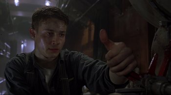 Movie still from “U-571” (2000), directed by Jonathan Mostow – A young man giving a thumbs up in a dark room; Close Up shot, Low angle