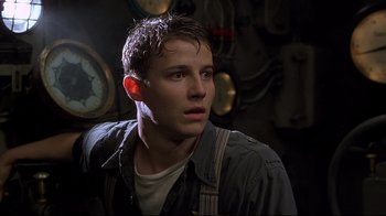 Movie still from “U-571” (2000), directed by Jonathan Mostow – A young man in a room with a clock in the background; Close Up shot, Low angle