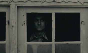 Movie still from “Ulysse” (1983), directed by Agnès Varda – A man looking out of a window in an old building; Close Up shot, Low angle