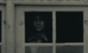 Movie still from “Ulysse” (1983), directed by Agnès Varda – A blurry image of a person looking out of a window; Extreme Close Up shot, Over the shoulder angle