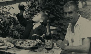 Movie still from “Ulysse” (1983), directed by Agnès Varda – A man and a boy sitting at a table with food; Medium shot, High angle