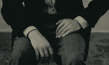 Movie still from “Ulysse” (1983), directed by Agnès Varda – A man sitting on the ground with his hands on his knees; Extreme Close Up shot, High angle