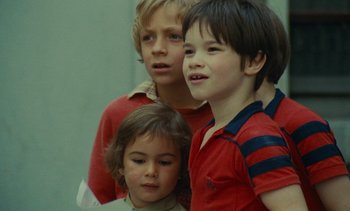 Movie still from “Ulysse” (1983), directed by Agnès Varda – Three young children standing next to each other in a room; Close Up shot, Low angle