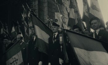 Movie still from “Ulysse” (1983), directed by Agnès Varda – A group of men in suits and hats holding flags; Medium shot, Low angle