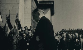 Movie still from “Ulysse” (1983), directed by Agnès Varda – An old black and white photo of a man in a crowd; Medium shot, Over the shoulder angle