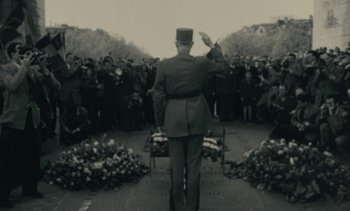 Movie still from “Ulysse” (1983), directed by Agnès Varda – A man in a military uniform saluting at a funeral; Wide shot, High angle