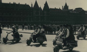 Movie still from “Ulysse” (1983), directed by Agnès Varda – A black and white photo of people on scooters; Extreme Wide shot, High angle