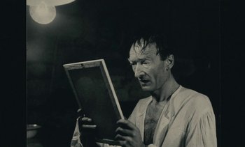Movie still from “Ulysse” (1983), directed by Agnès Varda – An old photo of a man looking at a book; Close Up shot, Over the shoulder angle