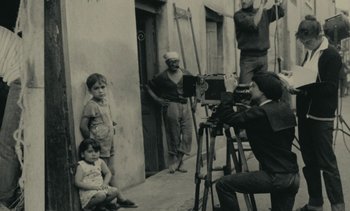 Movie still from “Ulysse” (1983), directed by Agnès Varda – An old black and white photo of a man taking a picture; Wide shot, High angle