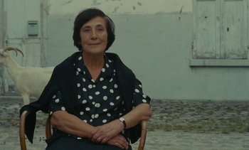 Movie still from “Ulysse” (1983), directed by Agnès Varda – An older woman sitting on a chair outside; Medium shot, Over the shoulder angle