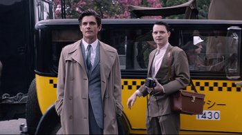 Movie still from “Unbroken: Path to Redemption” (2018), directed by Harold Cronk – Two men are standing in front of a yellow bus; Medium shot, Low angle