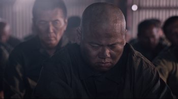 Movie still from “Unbroken: Path to Redemption” (2018), directed by Harold Cronk – A man with a shaved head is looking at the camera; Close Up shot, Over the shoulder angle