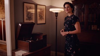 Movie still from “Unbroken: Path to Redemption” (2018), directed by Harold Cronk – A woman standing in front of an old fashioned record player; Medium shot, Over the shoulder angle