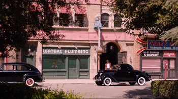 Movie still from “Unbroken: Path to Redemption” (2018), directed by Harold Cronk – An old car parked in front of a building; Extreme Wide shot, High angle