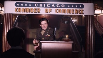 Movie still from “Unbroken: Path to Redemption” (2018), directed by Harold Cronk – A man in a military uniform is speaking at a podium; Medium shot, Low angle