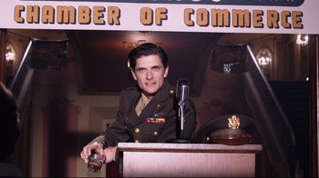 Movie still from “Unbroken: Path to Redemption” (2018), directed by Harold Cronk – A man in a military uniform is holding a glass of beer; Medium shot, Low angle