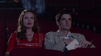 Movie still from “Unbroken: Path to Redemption” (2018), directed by Harold Cronk – A man and a woman sitting next to each other in a movie theater; Medium shot, Low angle