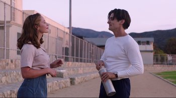 Movie still from “Unbroken: Path to Redemption” (2018), directed by Harold Cronk – A man and a woman standing next to each other on a sidewalk; Medium shot, Over the shoulder angle