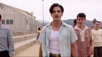 Movie still from “Unbroken: Path to Redemption” (2018), directed by Harold Cronk – A man in a white tank top and a blue shirt; Medium shot, Low angle