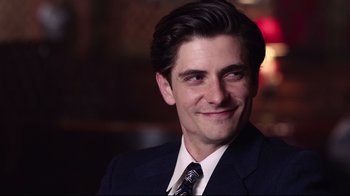 Movie still from “Unbroken: Path to Redemption” (2018), directed by Harold Cronk – A person wearing a suit and tie; Close Up shot, Over the shoulder angle