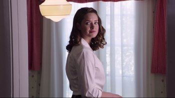 Movie still from “Unbroken: Path to Redemption” (2018), directed by Harold Cronk – A woman standing in front of a window with curtains; Medium shot, Low angle