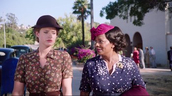 Movie still from “Unbroken: Path to Redemption” (2018), directed by Harold Cronk – Two women wearing hats standing next to each other on the street; Medium shot, Over the shoulder angle
