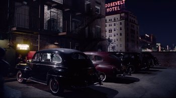 Movie still from “Unbroken: Path to Redemption” (2018), directed by Harold Cronk – A group of old cars parked in front of a hotel; Extreme Wide shot, High angle