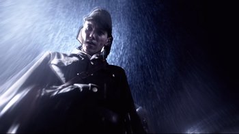 Movie still from “Unbroken: Path to Redemption” (2018), directed by Harold Cronk – A man in a rain jacket and hat standing in the rain; Medium shot, Low angle