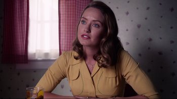 Movie still from “Unbroken: Path to Redemption” (2018), directed by Harold Cronk – A woman sitting at a table with a banana; Medium shot, Over the shoulder angle