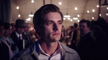 Movie still from “Unbroken: Path to Redemption” (2018), directed by Harold Cronk – A person with a crowd in the background; Close Up shot, Low angle