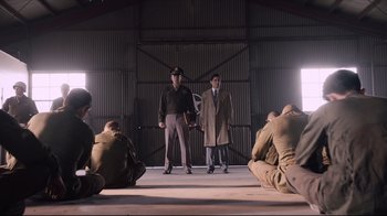 Movie still from “Unbroken: Path to Redemption” (2018), directed by Harold Cronk – A group of men sitting on the ground in front of each other; Wide shot, Low angle