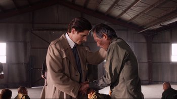 Movie still from “Unbroken: Path to Redemption” (2018), directed by Harold Cronk – A man in a suit and tie and a man in a suit and tie; Medium shot, Over the shoulder angle