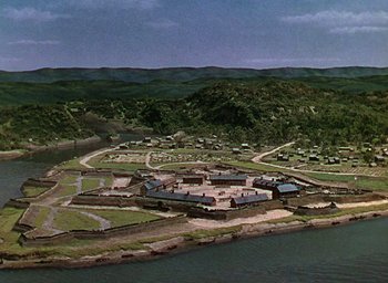 Movie still from “Unconquered” (1947), directed by Cecil B. DeMille – An aerial view of an island with houses on it's land; Extreme Wide shot, High angle