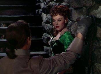 Movie still from “Unconquered” (1947), directed by Cecil B. DeMille – A woman in a green dress and a man in a black suit; Medium shot, Over the shoulder angle