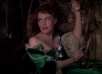 Movie still from “Unconquered” (1947), directed by Cecil B. DeMille – A woman in a green dress sitting on a chair; Medium shot, High angle